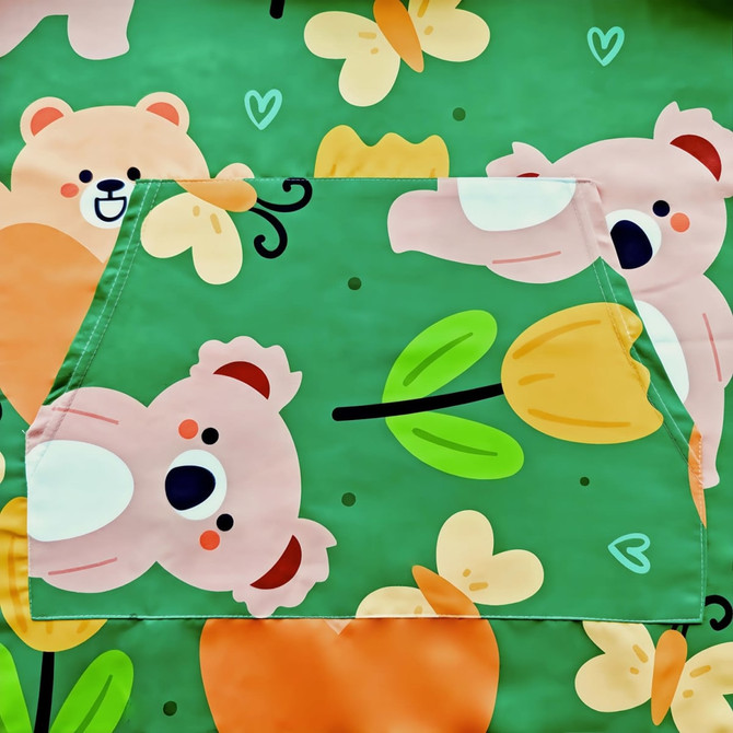 A hooded towel poncho featuring a playful design with koalas and flowers on a green background.