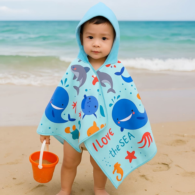 A hooded towel featuring a blue and aqua design with ocean-themed graphics. It has a logo and is worn by a child at the beach.