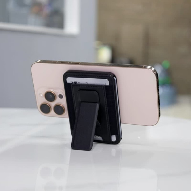 A phone with a black wallet case and kickstand, resting on a marble surface, featuring visible credit cards.