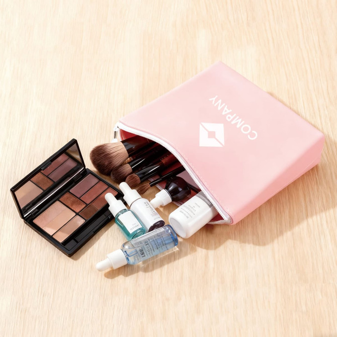 A pink silicone cosmetic pouch filled with various makeup items, including palettes, brushes, and skincare bottles.