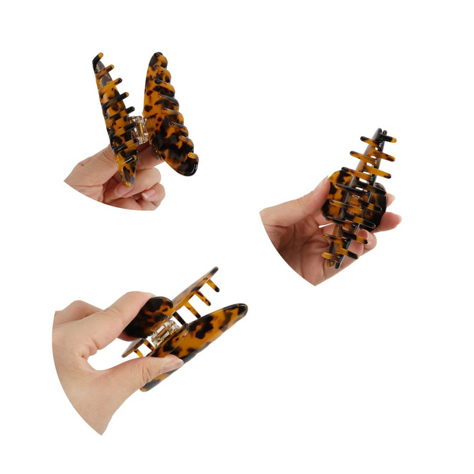 A set of tortoiseshell acetate hair clips being held in hand, showcasing their design and structure.