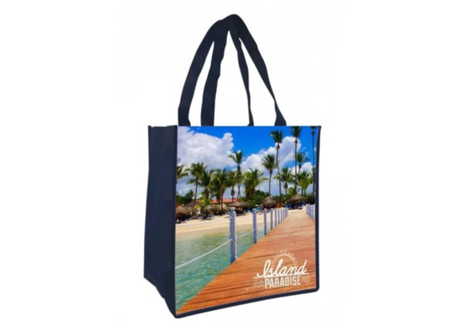 A navy tote bag featuring a vibrant beach scene with palm trees and a wooden boardwalk, including a logo.