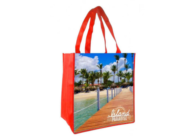 A red tote bag featuring a full-colour image of a tropical beach scene with palm trees and a wooden walkway.