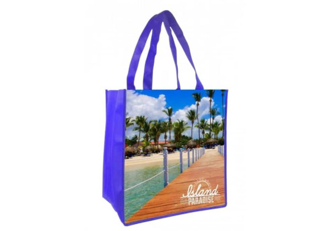 A purple tote bag featuring a full-colour beach scene with palm trees and a wooden walkway. It includes a logo.