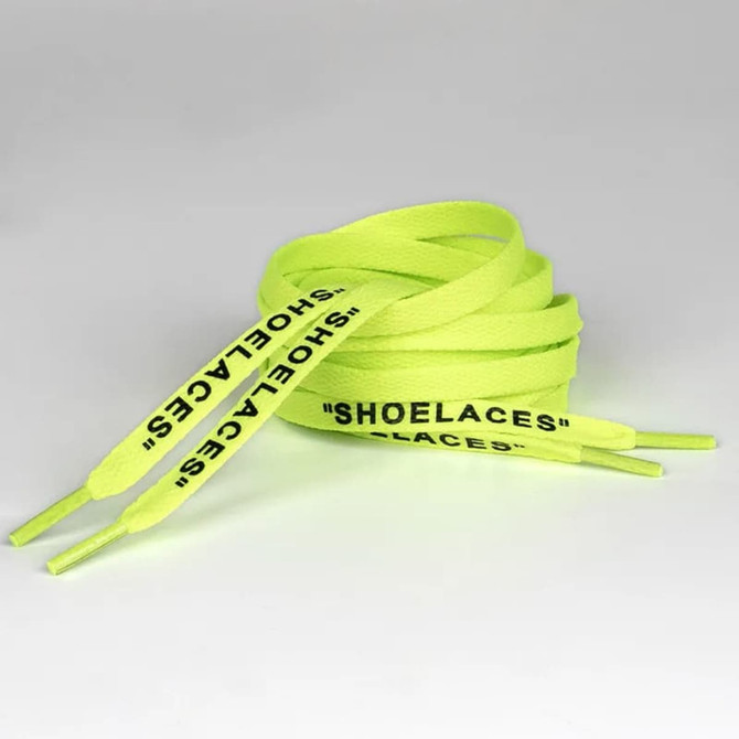 A pair of bright neon yellow shoelaces with printed text along the length.