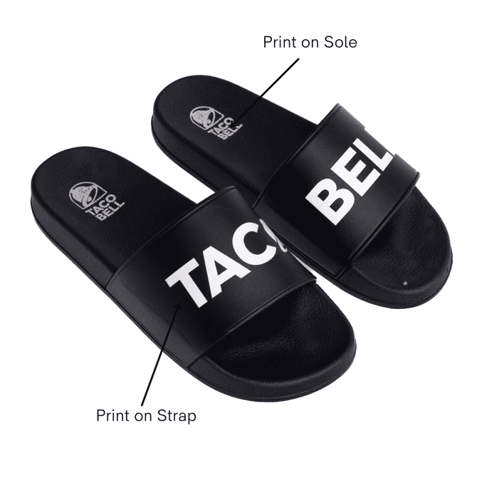 A pair of black PVC slides featuring a prominent logo and text printed on the strap and sole.