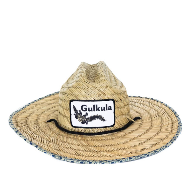 A straw hat with a wide brim, featuring a logo and decorative band around the base, in natural straw colour.