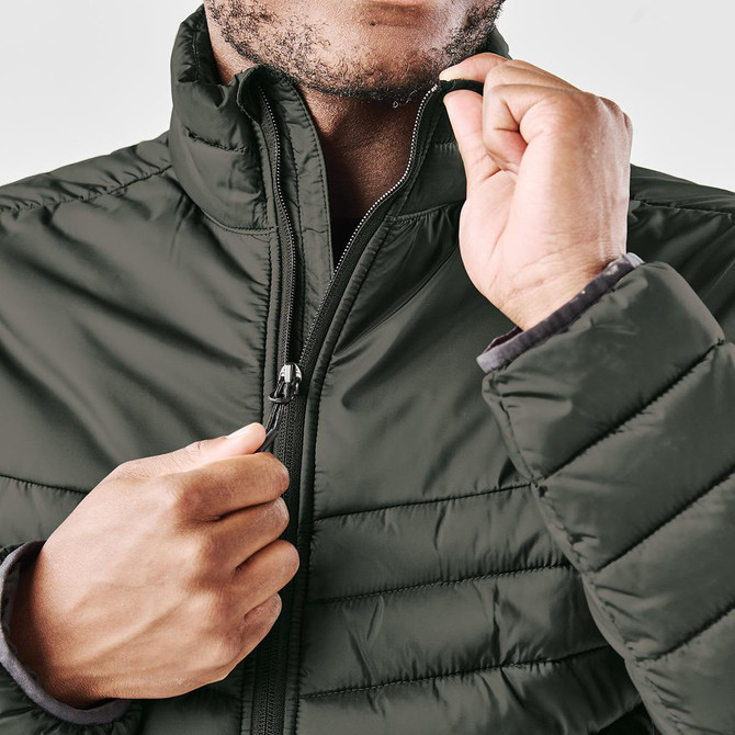 A close-up of a man wearing a dark green thermal jacket with a zippered front and a high collar.
