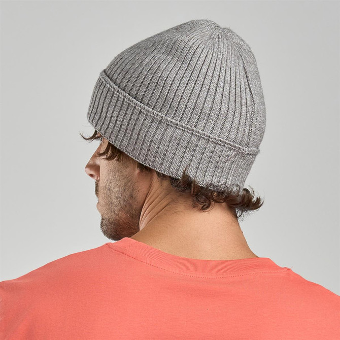 A grey ribbed beanie displayed on a model's head, featuring a logo on the side.