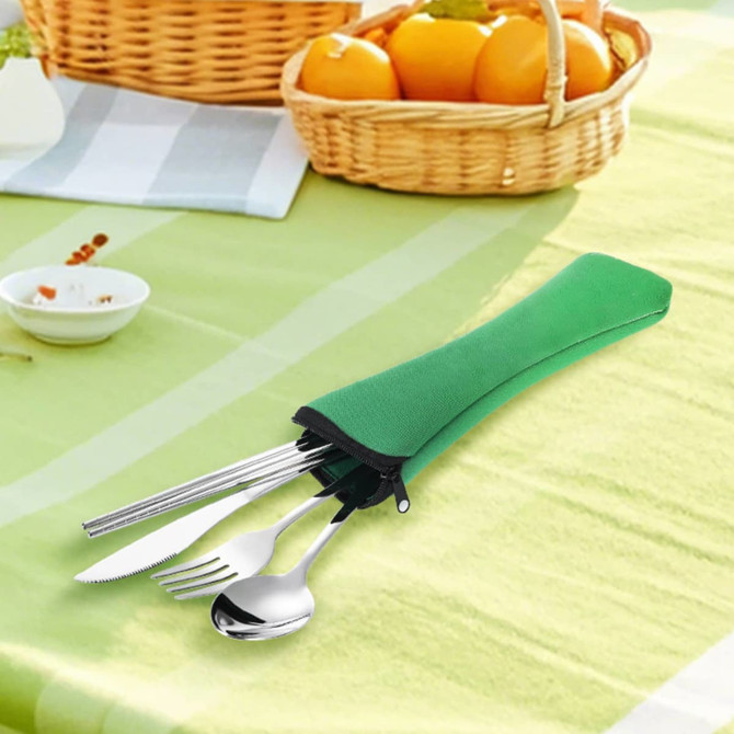 A green travel cutlery set featuring a knife, fork, spoon, and chopsticks, placed on a table with fruit.