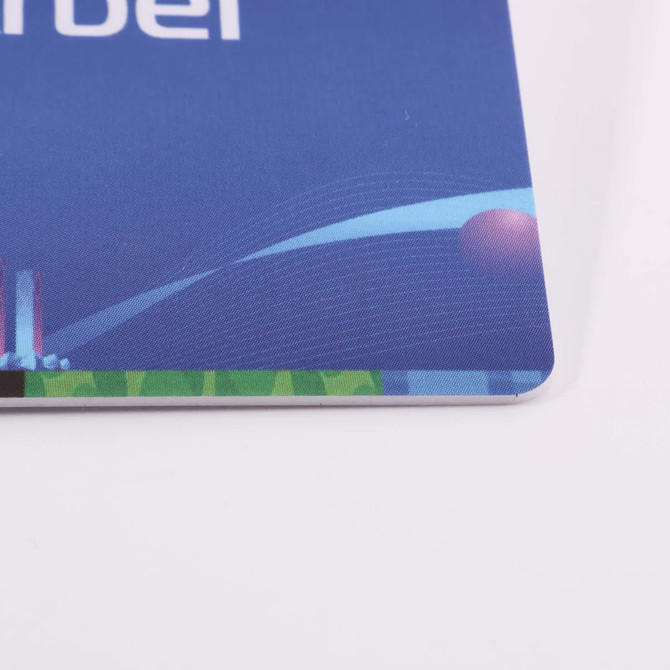 A close-up of a custom PVC name badge with a blue background and rounded corners, featuring a logo.