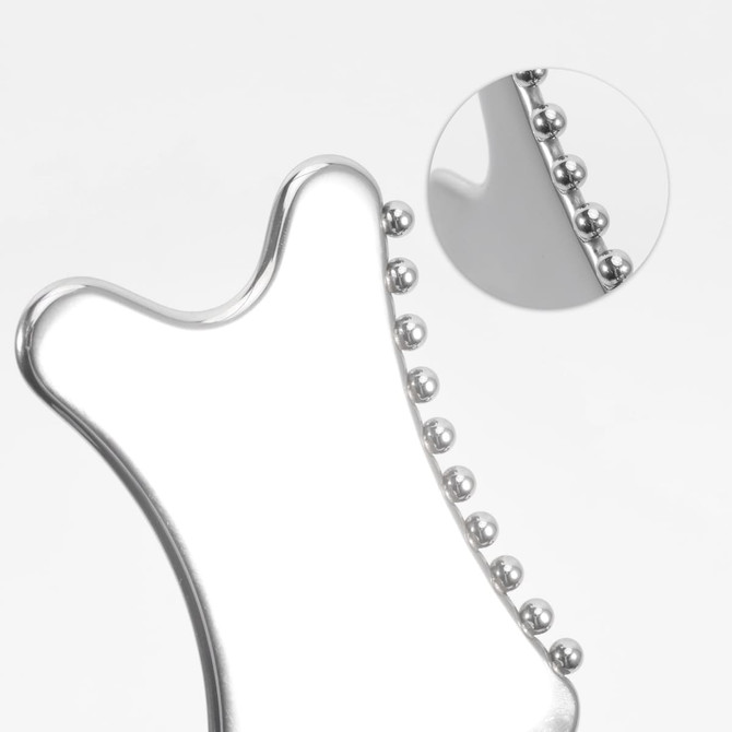 A silver Gua Sha tool with rounded edges and small beads along one side, featuring a close-up detail of the beads.