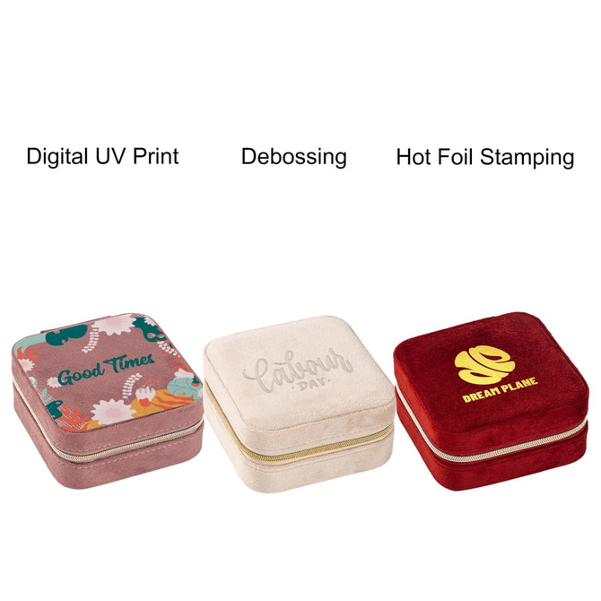 Three square velvet jewellery organisers in pink, cream, and red with decorative designs and a logo on each.
