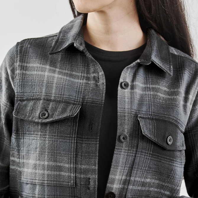 A stylish women's shacket featuring a black and grey Highland plaid pattern with buttoned pockets.