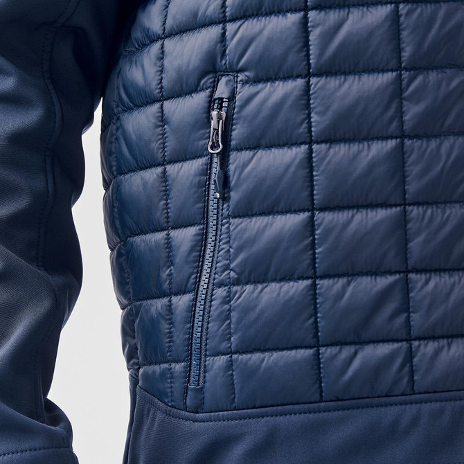 A navy thermal softshell jacket featuring a quilted texture and a zippered pocket on the side.