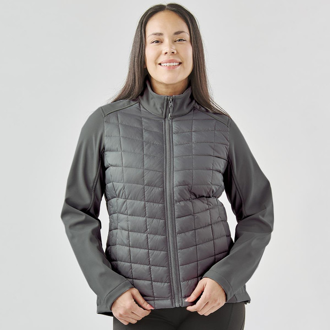 A women's softshell jacket in grey with a quilted front and long sleeves. Features a zip-up front and a logo.