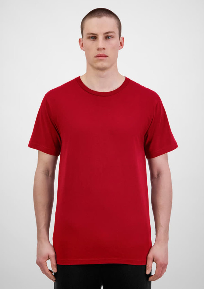 A man stands wearing a red short sleeve t-shirt. The t-shirt has a simple design and features a logo.
