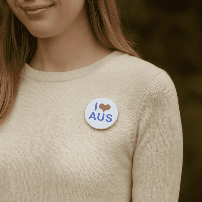 A button badge, 56mm in diameter, featuring a design with blue text and a heart shape on a white background.