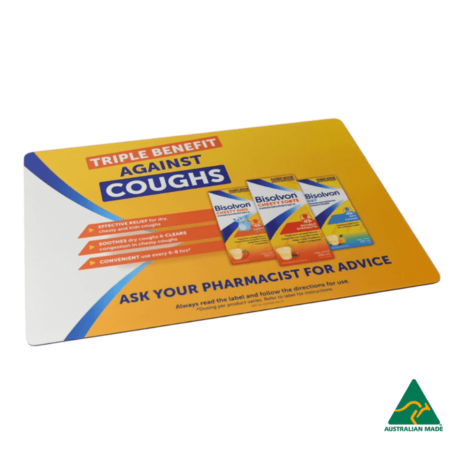 A rectangular counter mat with a yellow and blue design featuring cough relief products and a logo in the corner.
