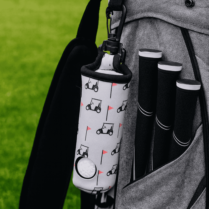 A neoprene golf ball sleeve with a golf cart design, attached to a grey golf bag alongside black golf club grips.