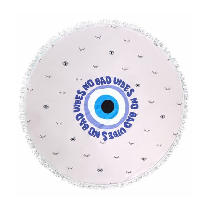 A round beach towel featuring a light background with eye patterns and fringe edges, and decorative text design.
