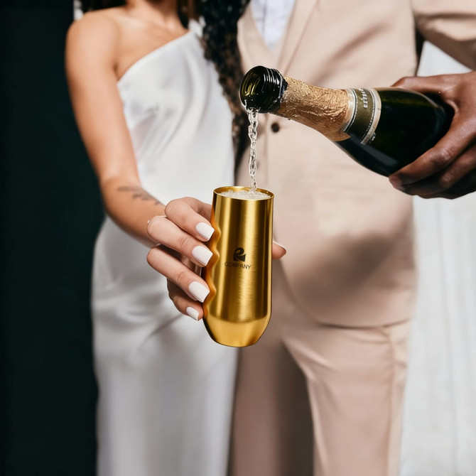 A gold vacuum champagne flute being filled with champagne, held by a person in formal attire.