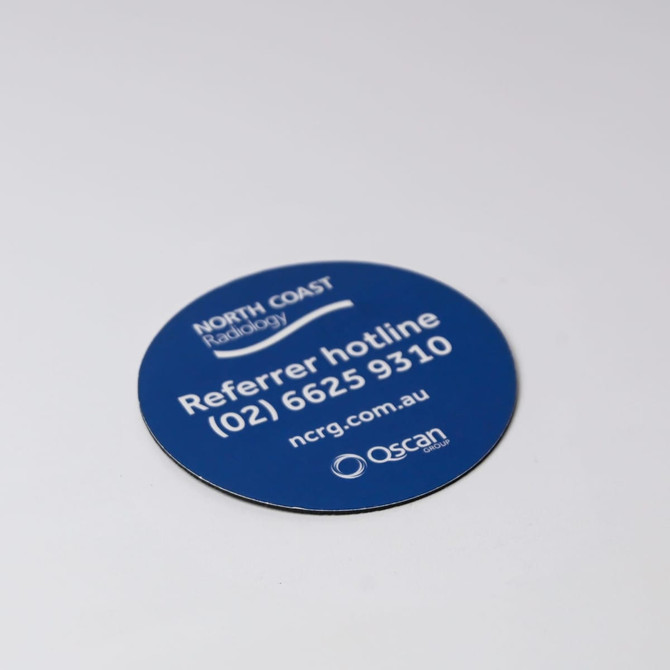 A round, blue coaster featuring a logo and contact information, with a smooth, glossy finish.