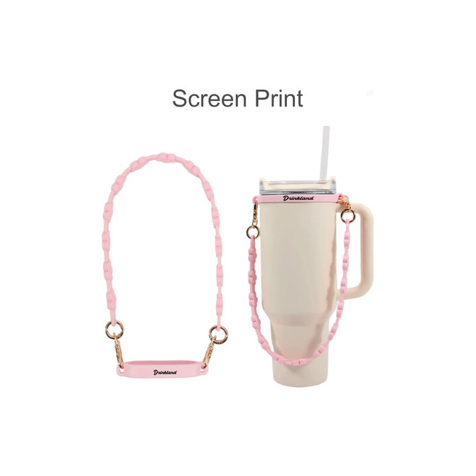 A drink bottle with a cream coloured body, paired with a pink silicone flower tumbler strap and gold clips.