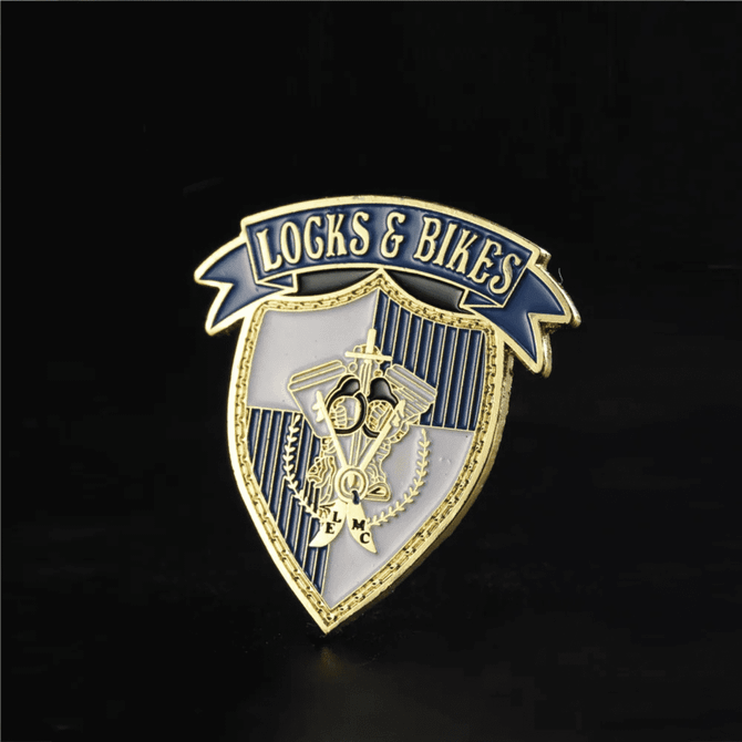 A custom enamel lapel pin featuring a gold and blue shield design with decorative elements and a logo.