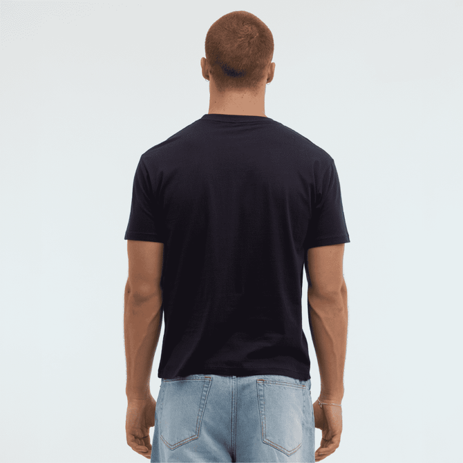 A navy Essential/Surf Tee displayed from the back on a model, wearing light blue jeans. The tee has a logo.