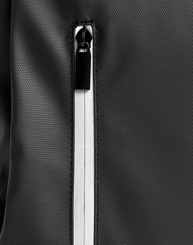 A close-up of a black backpack featuring a zippered compartment with a contrasting white zipper.