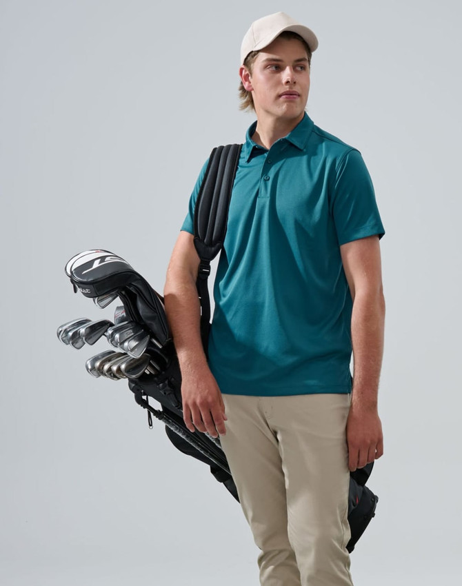 A person wearing a teal polo shirt and beige pants holds a golf bag with clubs, topped with a light-coloured cap.