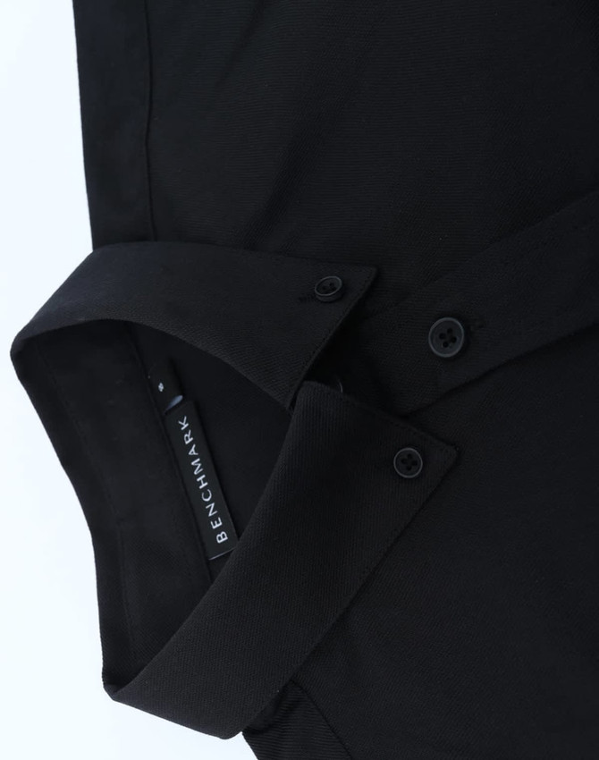 A black cotton blend long-sleeve shirt with a collar and button details, featuring a logo tag.