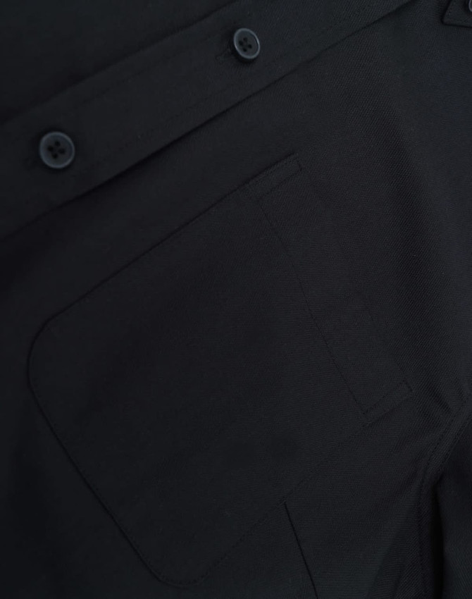 A close-up of a black cotton blend shirt featuring buttons and a pocket detail.
