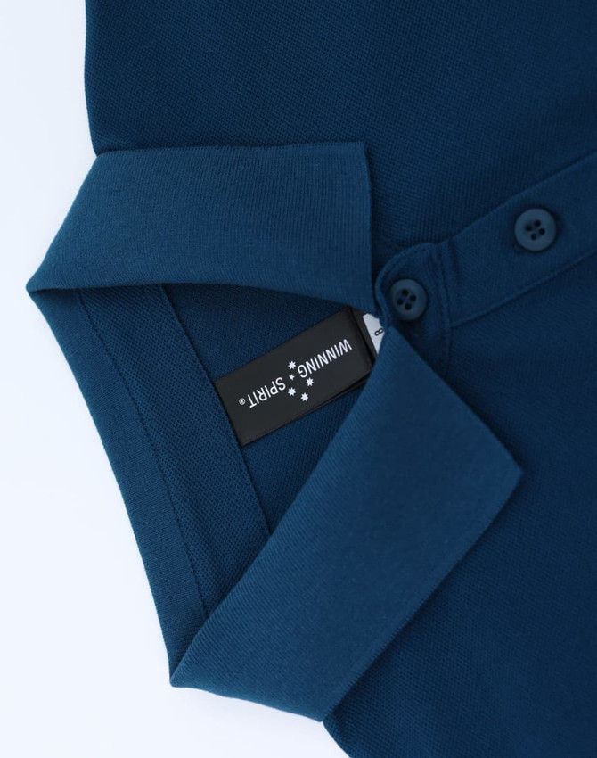 A navy blue ladies polo shirt with a collared neckline and buttons, featuring a brand tag inside.