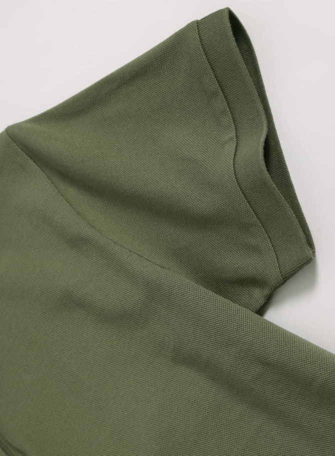 A green ladies ultrafine cotton pique polo, featuring a folded sleeve with a smooth texture and branding detail.