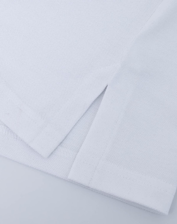 A close-up of a white ultrafine cotton pique polo, featuring textured fabric and neatly folded hems.