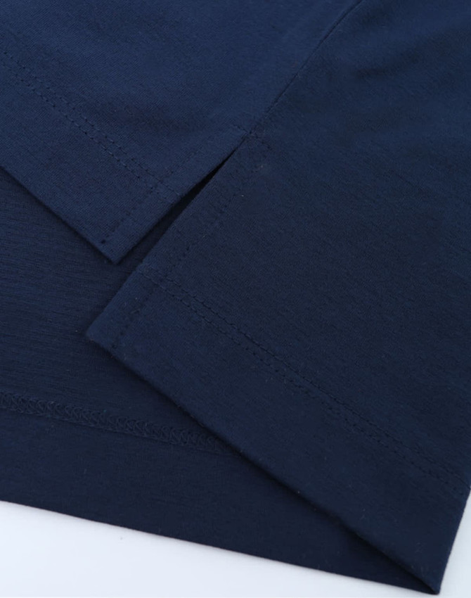 A close-up of a navy blue polo shirt displaying its fabric and hem details. The shirt has a logo.