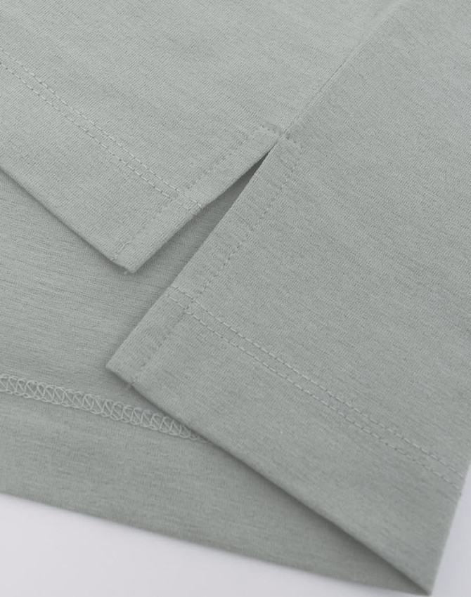 A close-up of a light grey polo shirt featuring short sleeves and a curved hemline. The fabric has a soft texture.