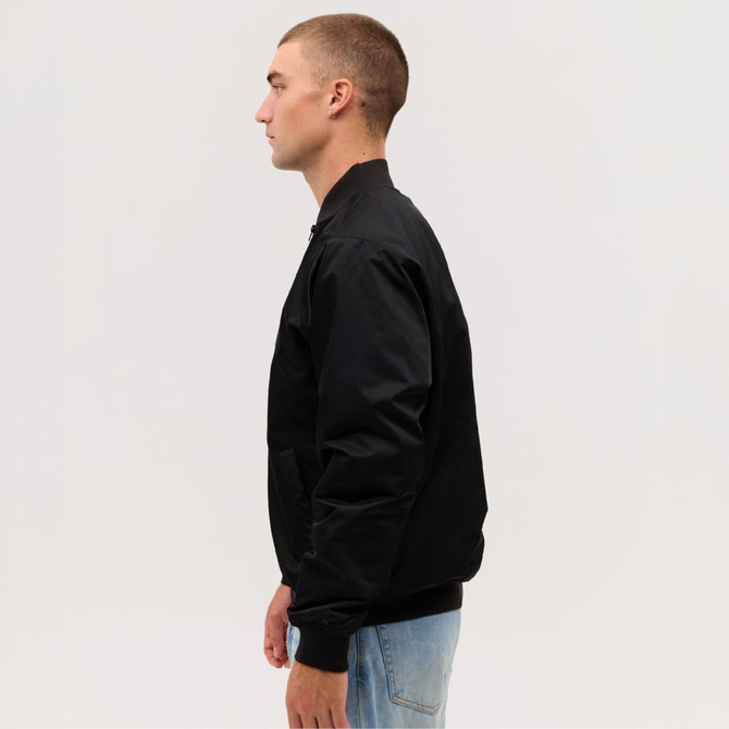 A black bomber jacket is displayed on a model viewed from the side, showcasing its sleek design and fit.