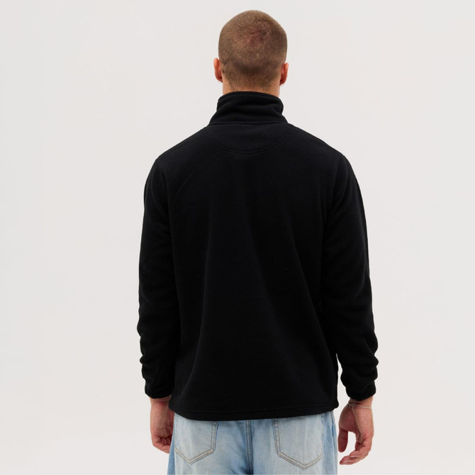 A black polar fleece 1/4 zip garment viewed from the back, worn by a person with short hair and a casual outfit.
