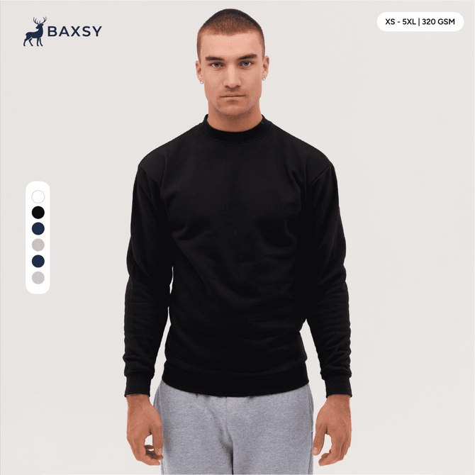 A crew sweatshirt in black, featuring long sleeves and a round neckline. The model is standing against a neutral background.