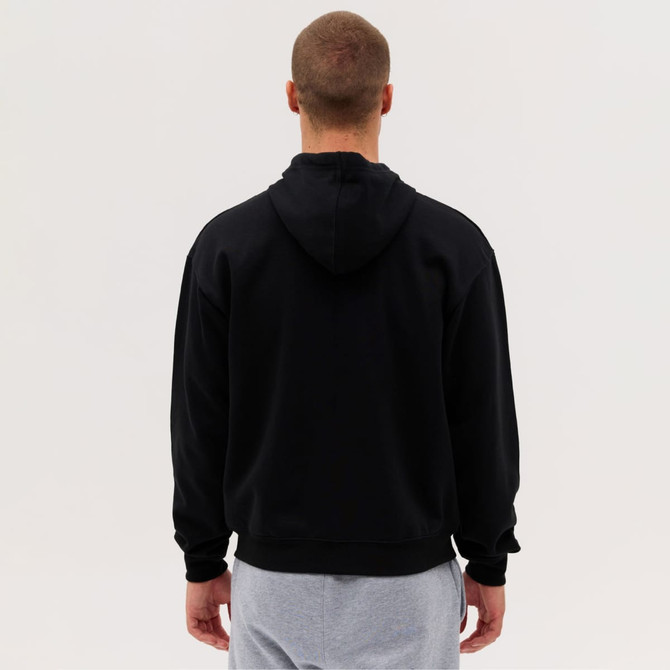 A black zip hoodie with a hood, viewed from the back, paired with light grey pants. It features a logo.