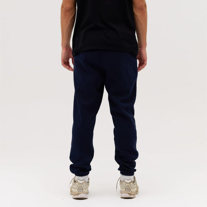 Navy blue track pants are displayed, featuring a casual fit and elastic cuffs, paired with a black shirt and light sneakers.