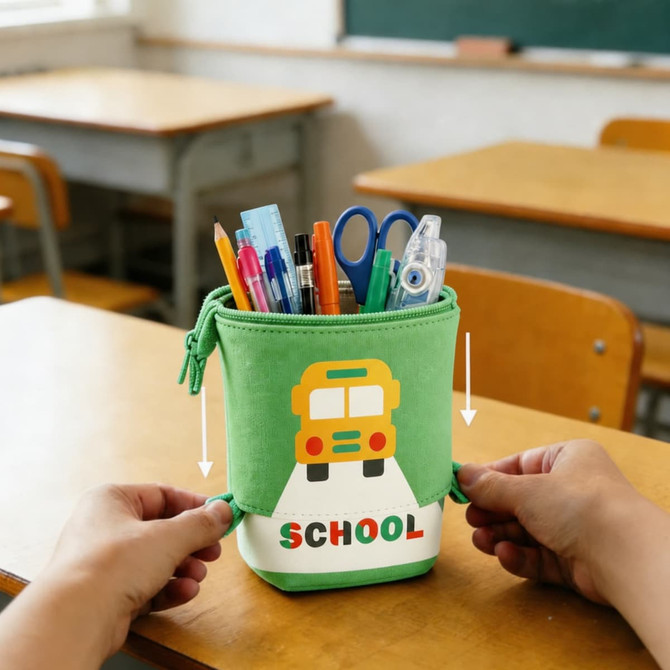 A green expandable pencil case featuring a school bus design, filled with pens, pencils, and scissors.