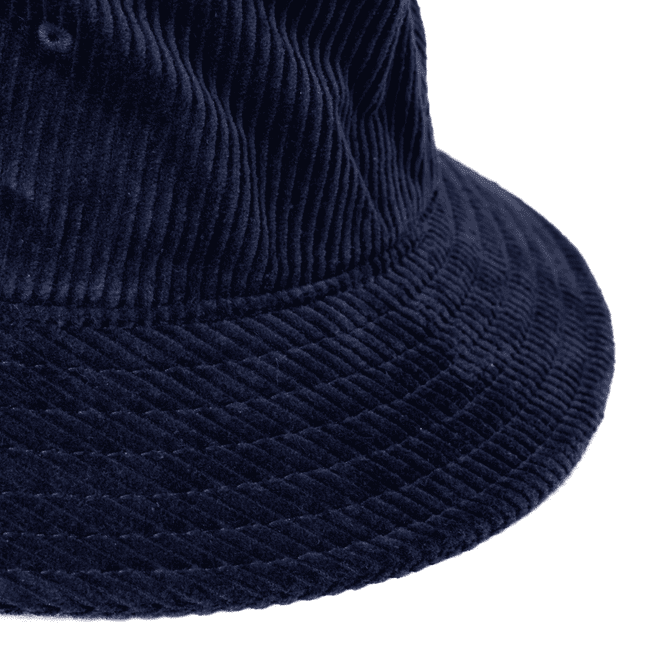 A navy cord bucket hat featuring a textured fabric and a wide brim. The hat includes a branding logo.