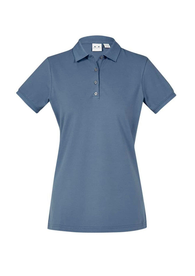 A women's short sleeve polo shirt in a soft blue colour, featuring a collar and button placket. It has a logo.