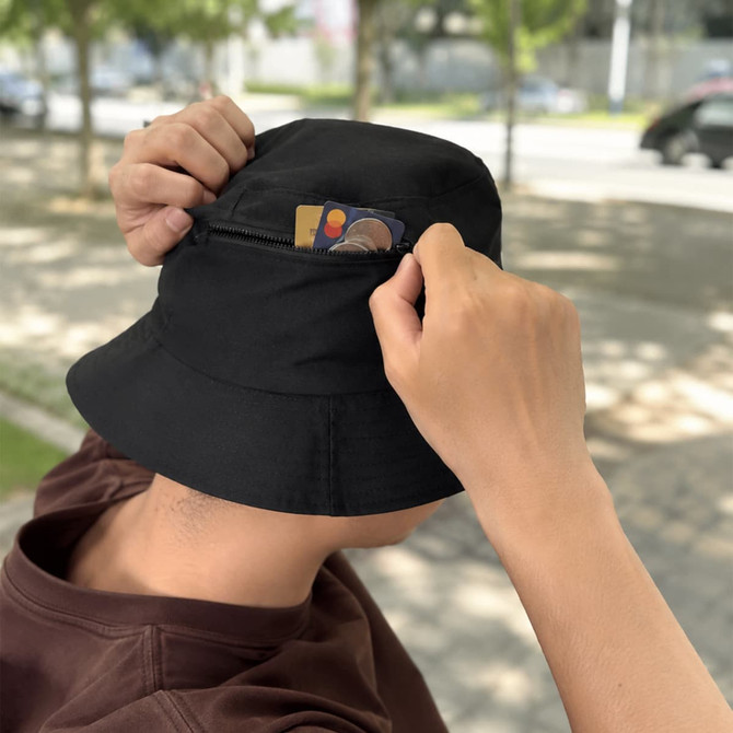 A black bucket hat with a card pocket, held by a person in a casual setting.