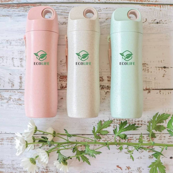 A drink bottle featuring three colours: pink, beige, and green, made from wheat straw, with a logo displayed.