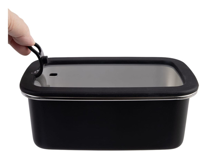 A hand holding the lid of a black rectangular stainless steel container with a clear plastic top.
